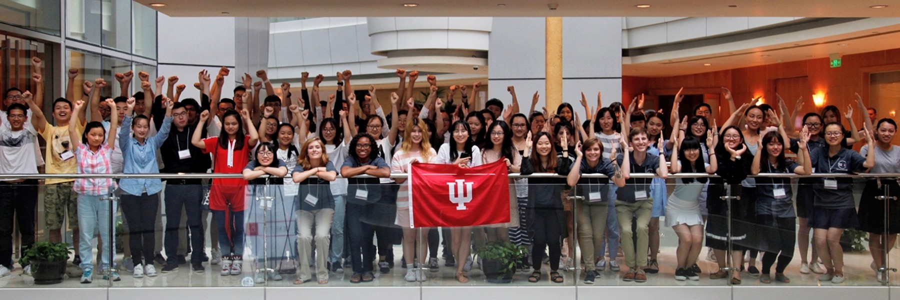 A large group photo of iu2u students in front of an IU flag